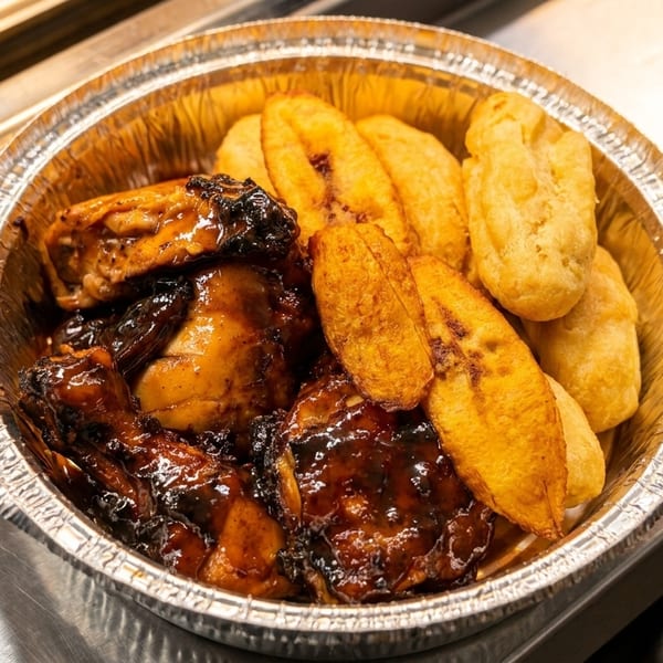 A foil container filled with glazed jerk chicken, fried plantains, and fried dumplings.
