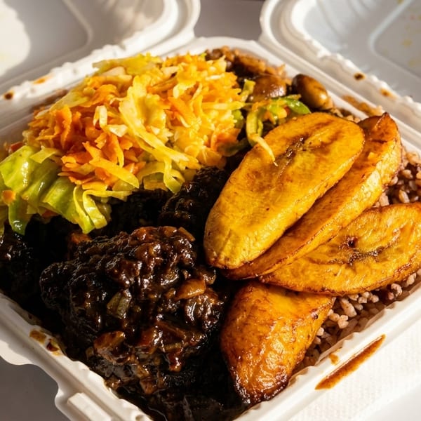 A takeout container filled with Jamaican oxtail, rice and peas, fried plantains, and steamed cabbage.